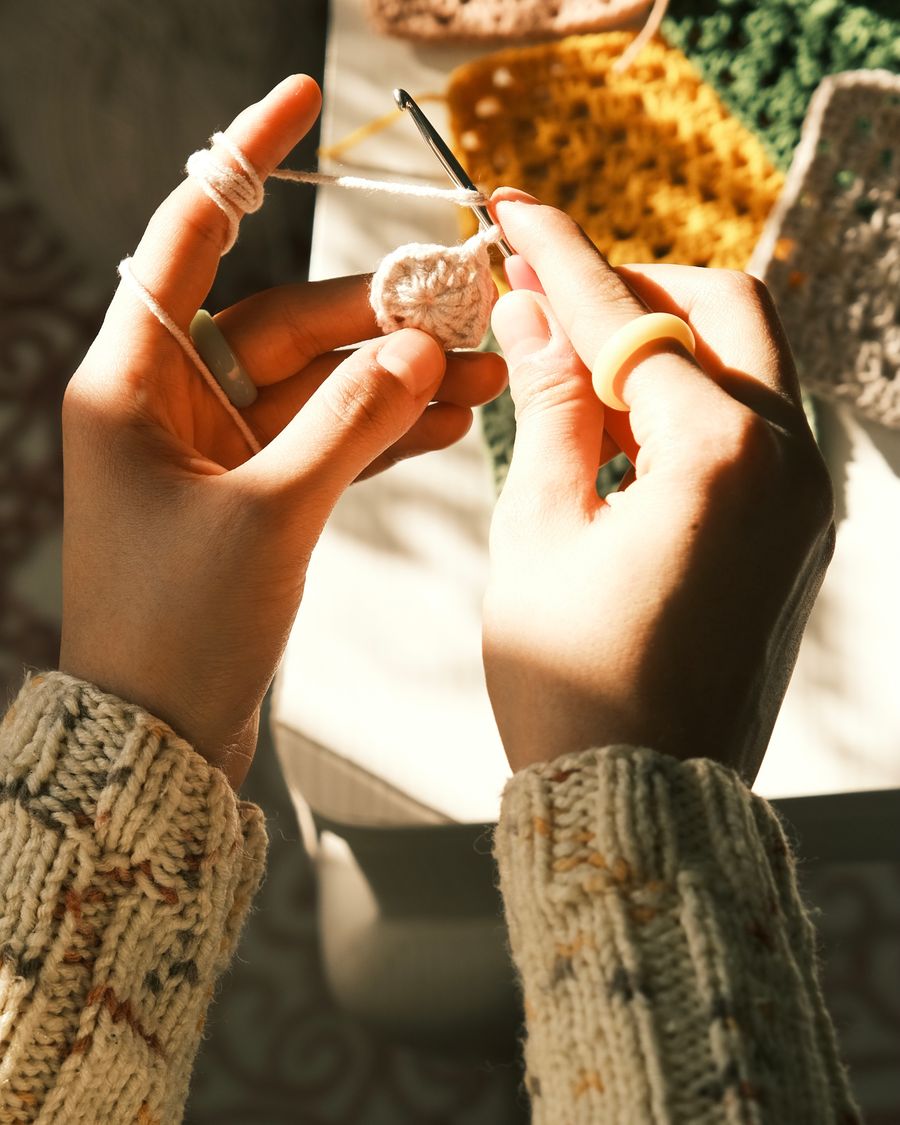 Three crochet granny squares in sage, cream and terracotta on white linen